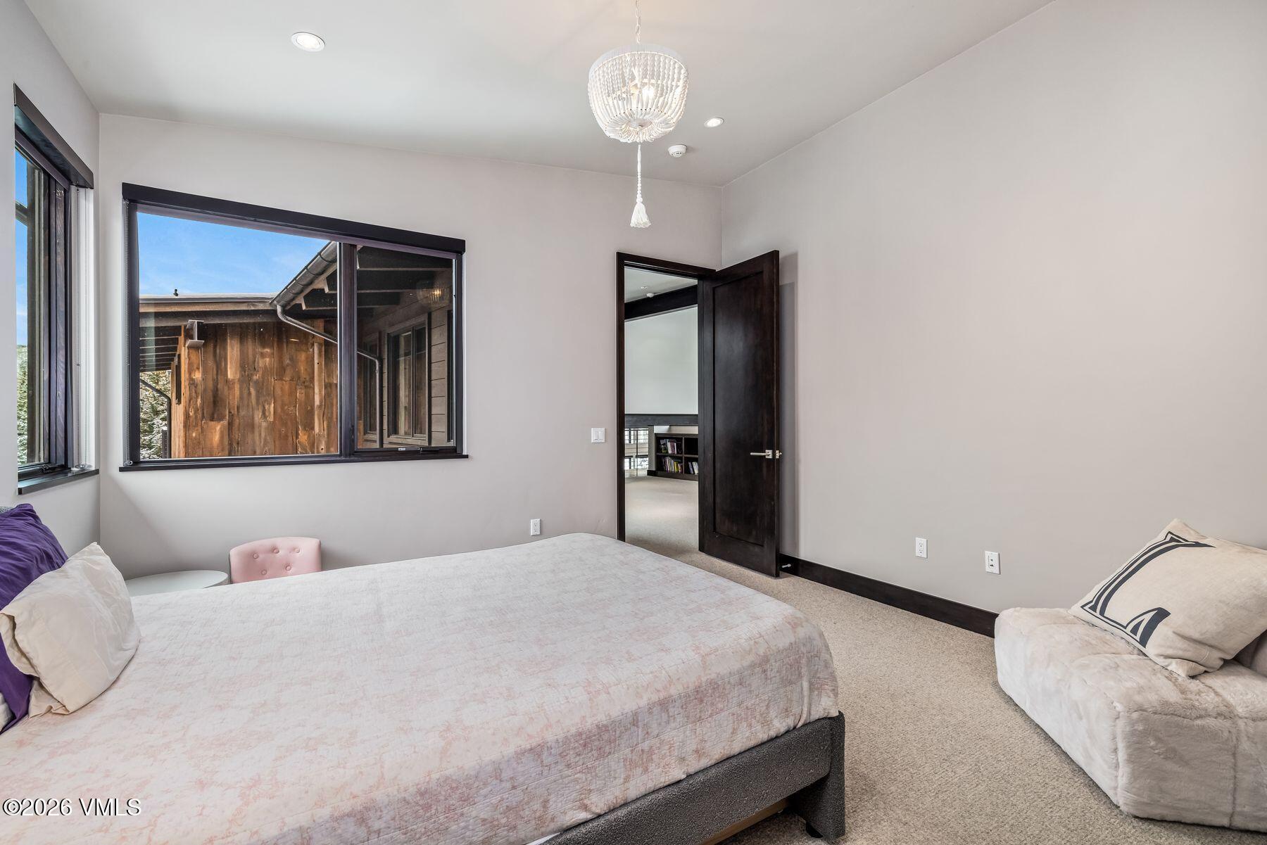 2440 Chamonix Lane Vail, CO 81657 - Photo 23 of 36 a bedroom with a large bed and a chandelier