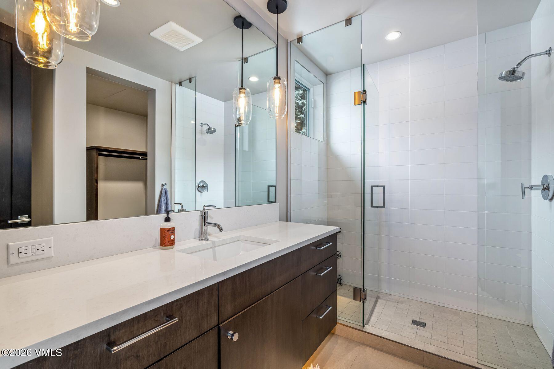 2440 Chamonix Lane Vail, CO 81657 - Photo 26 of 36 a bathroom with a shower sink vanity and mirror