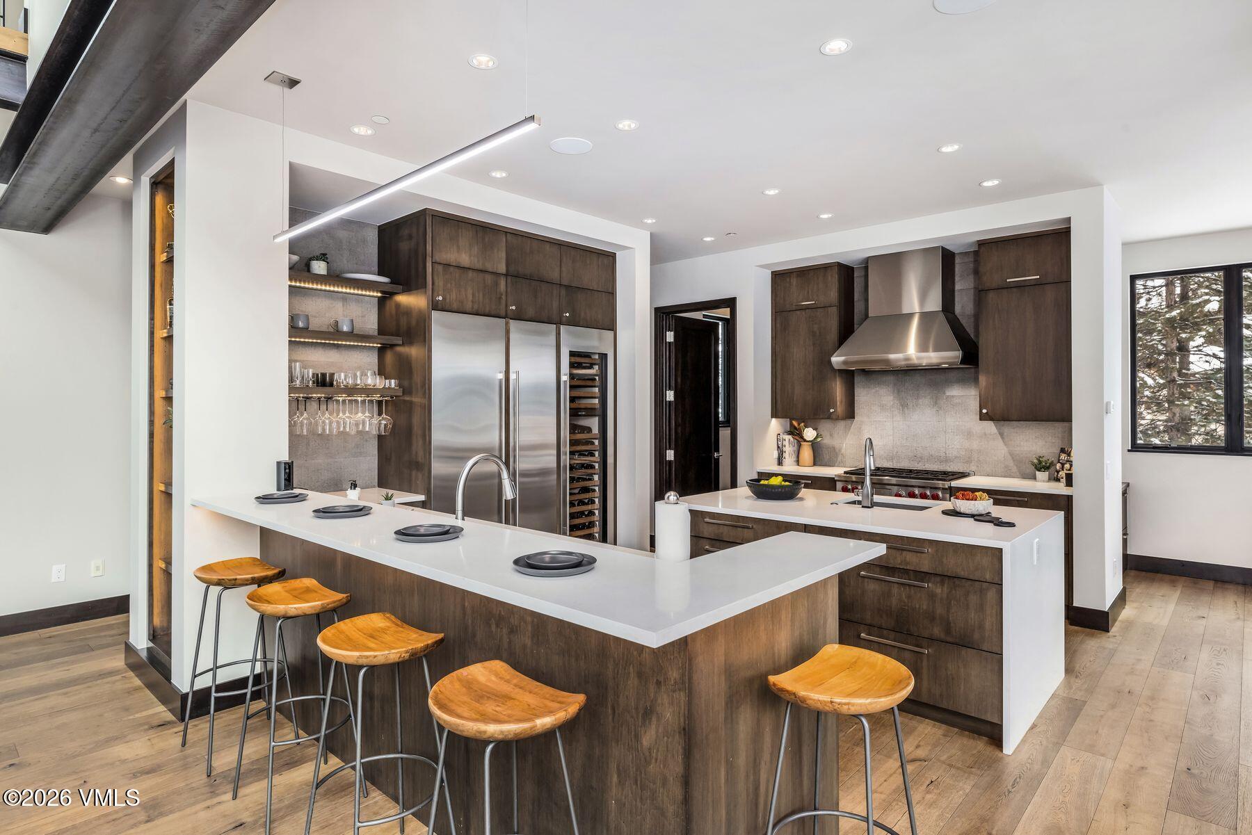 2440 Chamonix Lane Vail, CO 81657 - Photo 7 of 36 a kitchen with stainless steel appliances granite countertop a stove a sink dishwasher a dining table and chairs with wooden floor