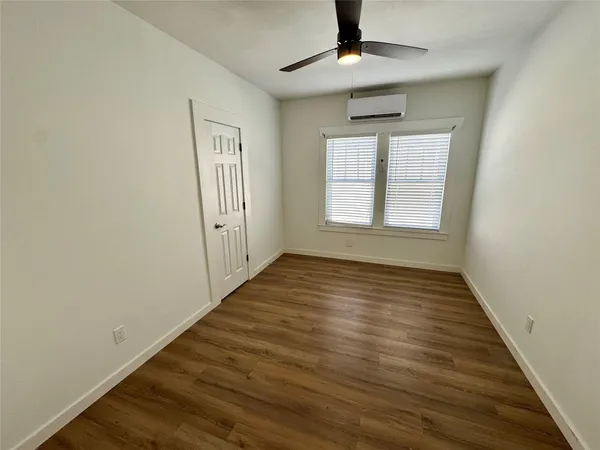 an empty room with wooden floor chandelier fan and windows