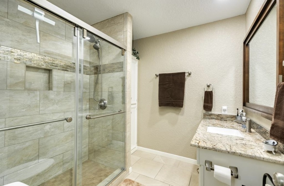 131 Bastrop Bayou Drive Angleton, TX 77515 - Photo 18 of 36 a bathroom with a granite countertop shower mirror and a sink
