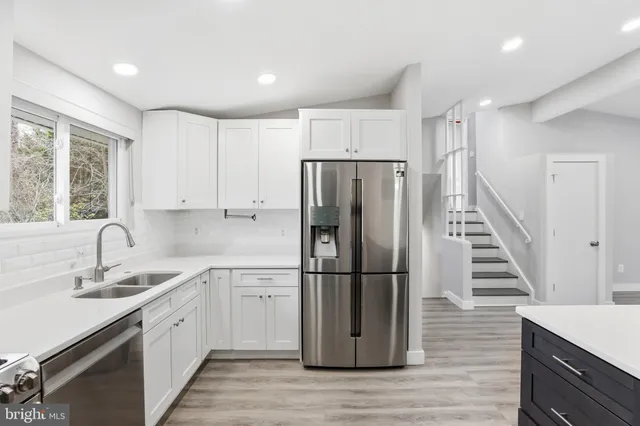 a kitchen with a refrigerator a sink cabinets and wooden floor