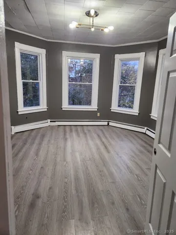 a view of an empty room with wooden floor and window