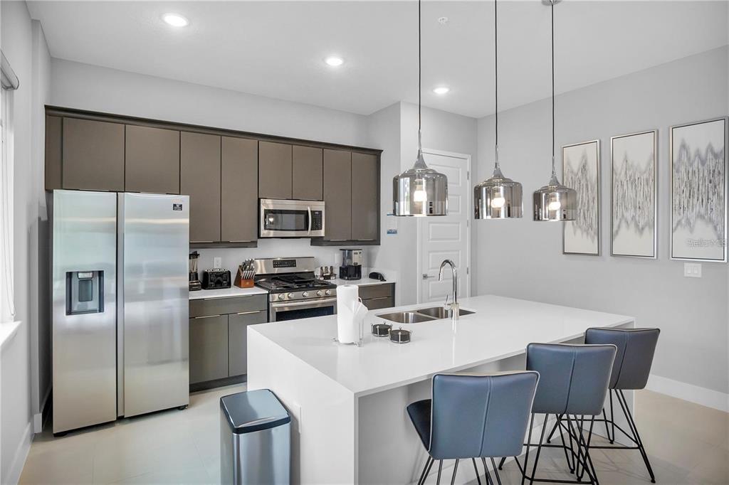 7740 Sandy Ridge Drive, Unit 106 Reunion, FL 34747 - Photo 6 of 43 a kitchen with stainless steel appliances a table chairs refrigerator and microwave