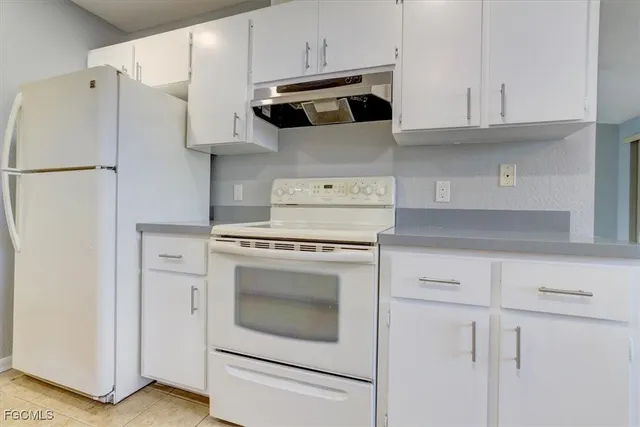 a kitchen with stainless steel appliances white cabinets and a refrigerator