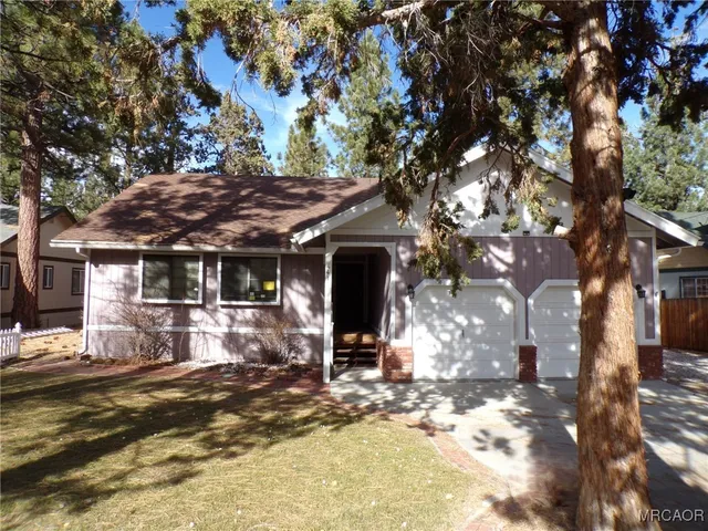 a view of a house with large trees and sitting area