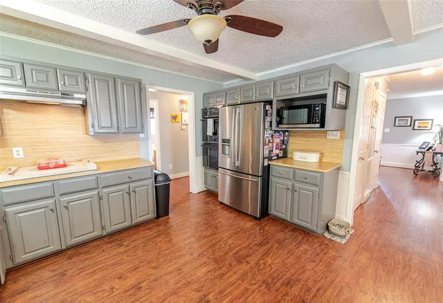 a kitchen with stainless steel appliances wooden floor and a refrigerator