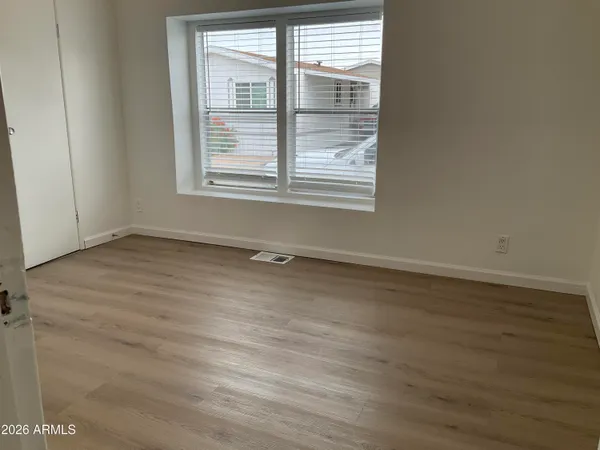 an empty room with wooden floor and windows