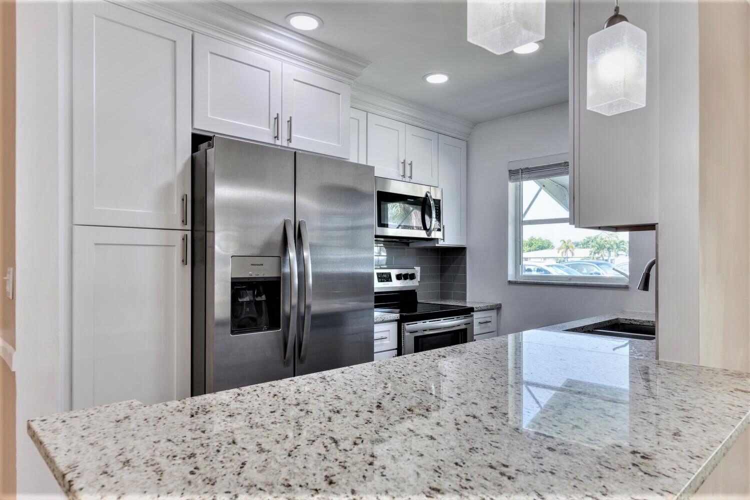 a kitchen with stainless steel appliances kitchen island granite countertop a refrigerator stove top oven and sink