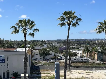 a front view of a multi story residential apartment building with yard and parking