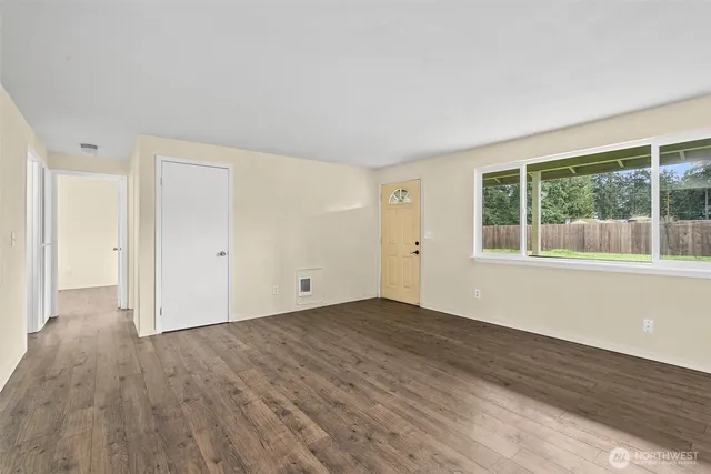 a view of an empty room with wooden floor and windows