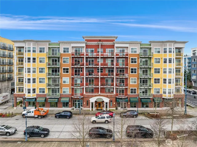 a front view of a building with lot of cars and trees