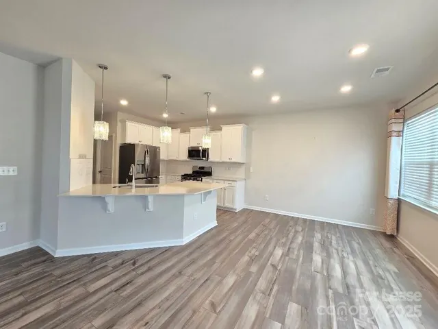 a view of kitchen with kitchen island wooden floor center island and stainless steel appliances