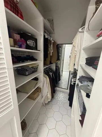 a view of walk in closet with clothes and shoes