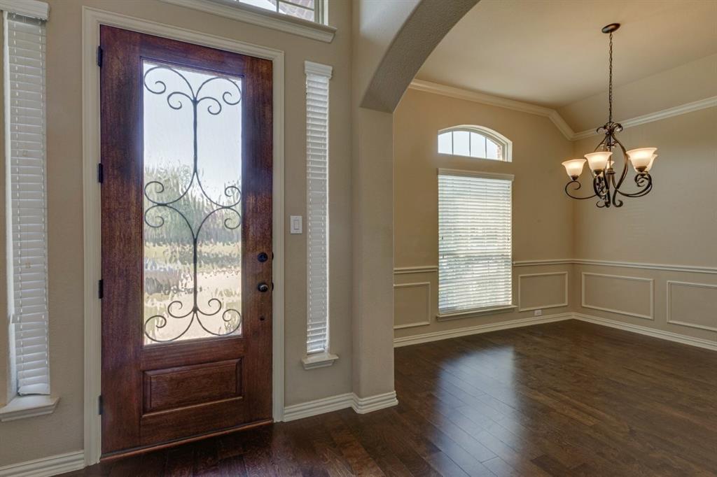 1522 Blue Jay Road Garland, TX 75043 - Photo 5 of 32 Hardwood-finish flooring extends from the entryway, featuring a wood-panel door with decorative ironwork and frosted glass
