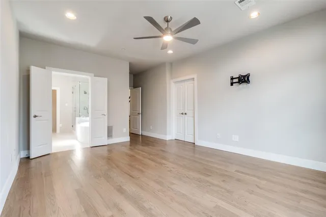 an empty room with wooden floor and a ceiling fan