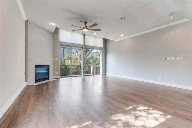 a view of an empty room with wooden floor fireplace and a window