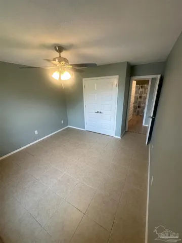 an empty room with a chandelier fan and windows