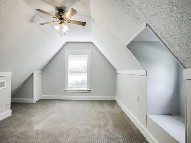 an empty room with a chandelier fan and windows