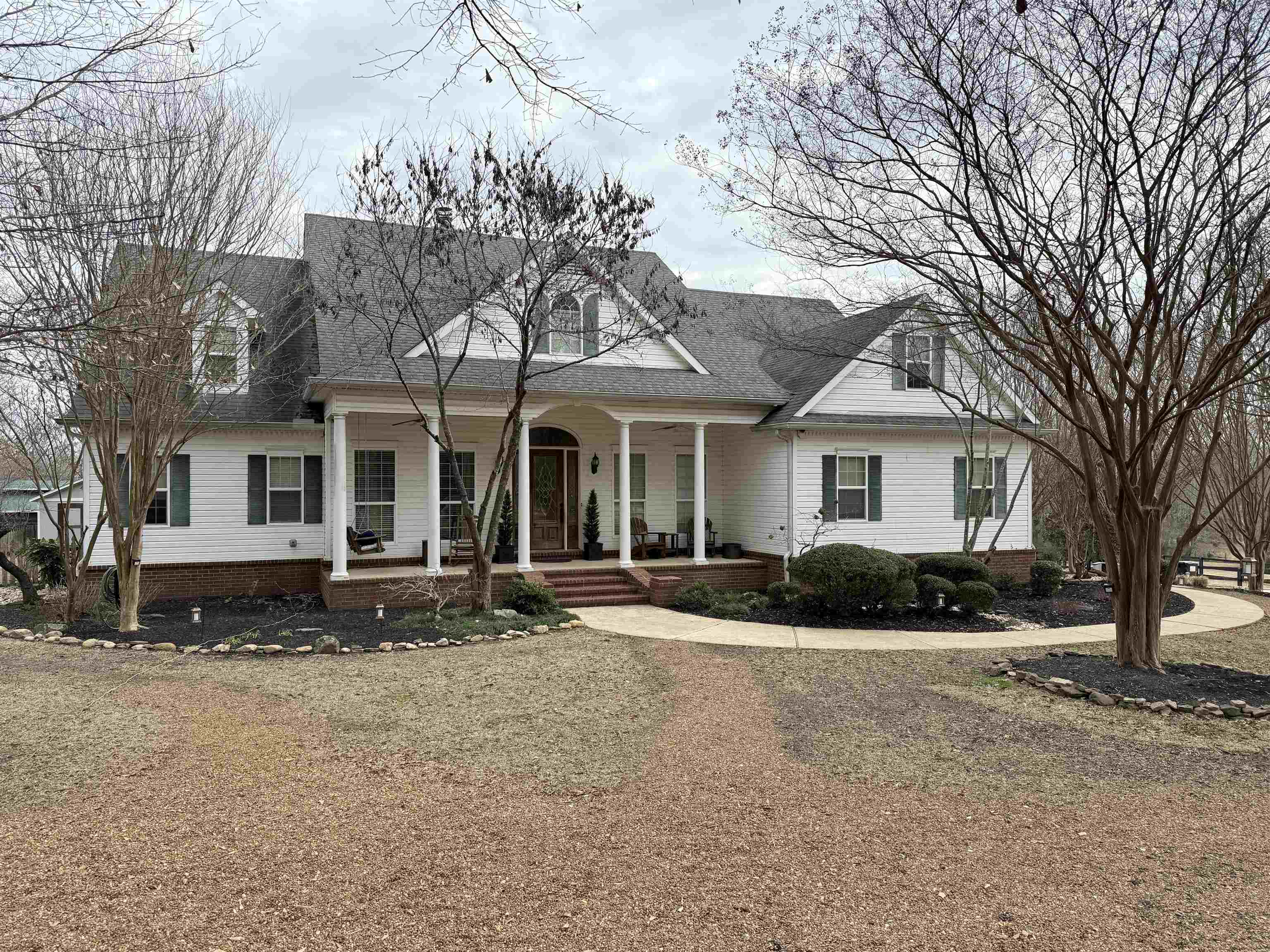 View of front facade featuring covered porch, roof with shingles, and a front lawn