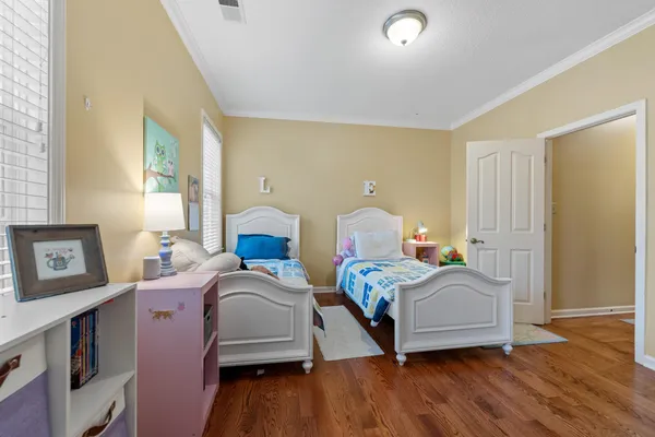 a bedroom with two beds and wooden floor