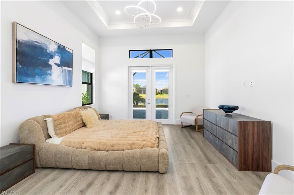 9675 Moonflower Court Naples, FL 34114 - Photo 16 of 32 Bedroom with access to exterior, light wood finished floors, french doors, a high ceiling, and a chandelier