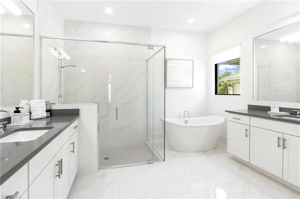 9675 Moonflower Court Naples, FL 34114 - Photo 17 of 32 Full bath featuring two vanities, a marble finish shower, a freestanding tub, light marble finish flooring, and recessed lighting