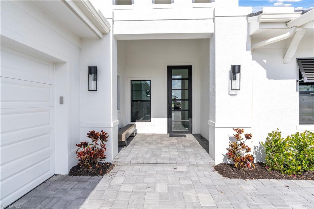 9675 Moonflower Court Naples, FL 34114 - Photo 2 of 32 Doorway to property featuring stucco siding and a garage