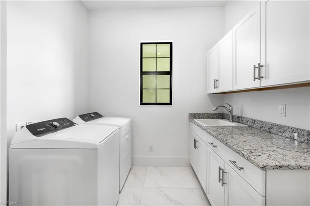a utility room with sink dryer and cabinets