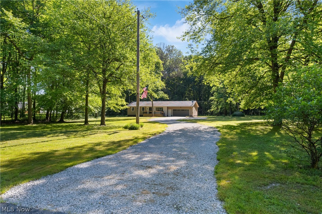 1075 Northeast River Road Lake Milton, OH 44429 - Photo 1 of 34 Gravel driveway approaching a single-story residence with an attached two-car garage