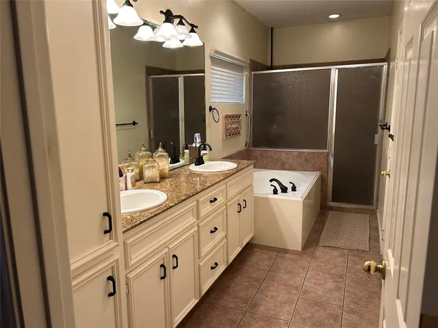 a bathroom with a double vanity sink mirror and bathtub