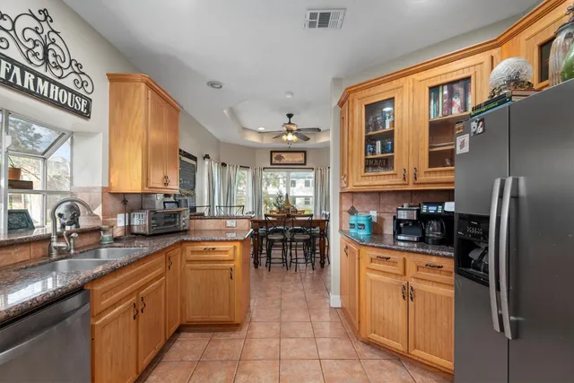 a kitchen with stainless steel appliances granite countertop a stove top oven a sink a dining table and chairs