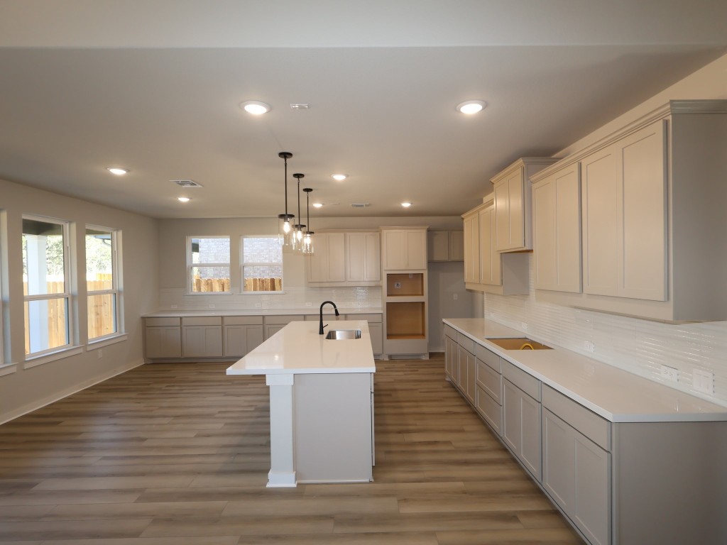 3713 Helena Way Leander, TX 78641 - Photo 5 of 28 a large kitchen with stainless steel appliances kitchen island a large counter top a sink a refrigerator and a window