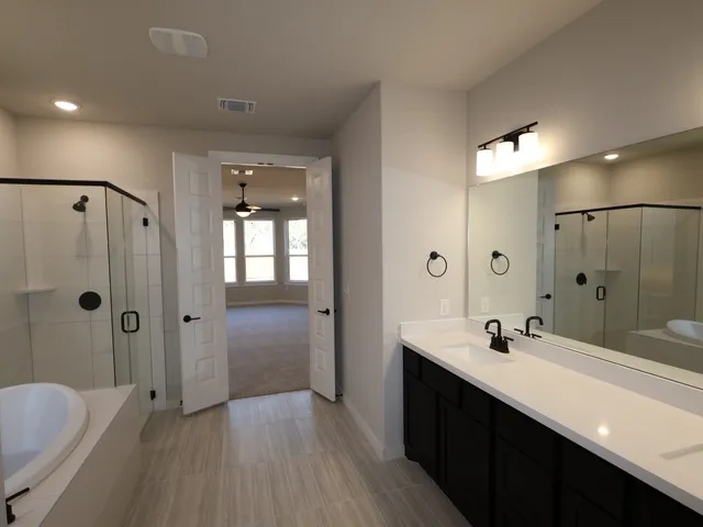 a bathroom with a double vanity sink a toilet a shower and a mirror