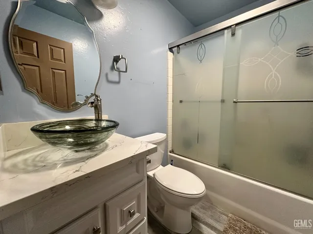 a bathroom with a granite countertop sink toilet and shower