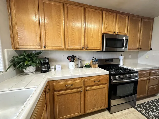 a kitchen with stainless steel appliances granite countertop a stove a sink and a microwave