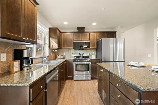 a kitchen with stainless steel appliances granite countertop a sink stove and refrigerator