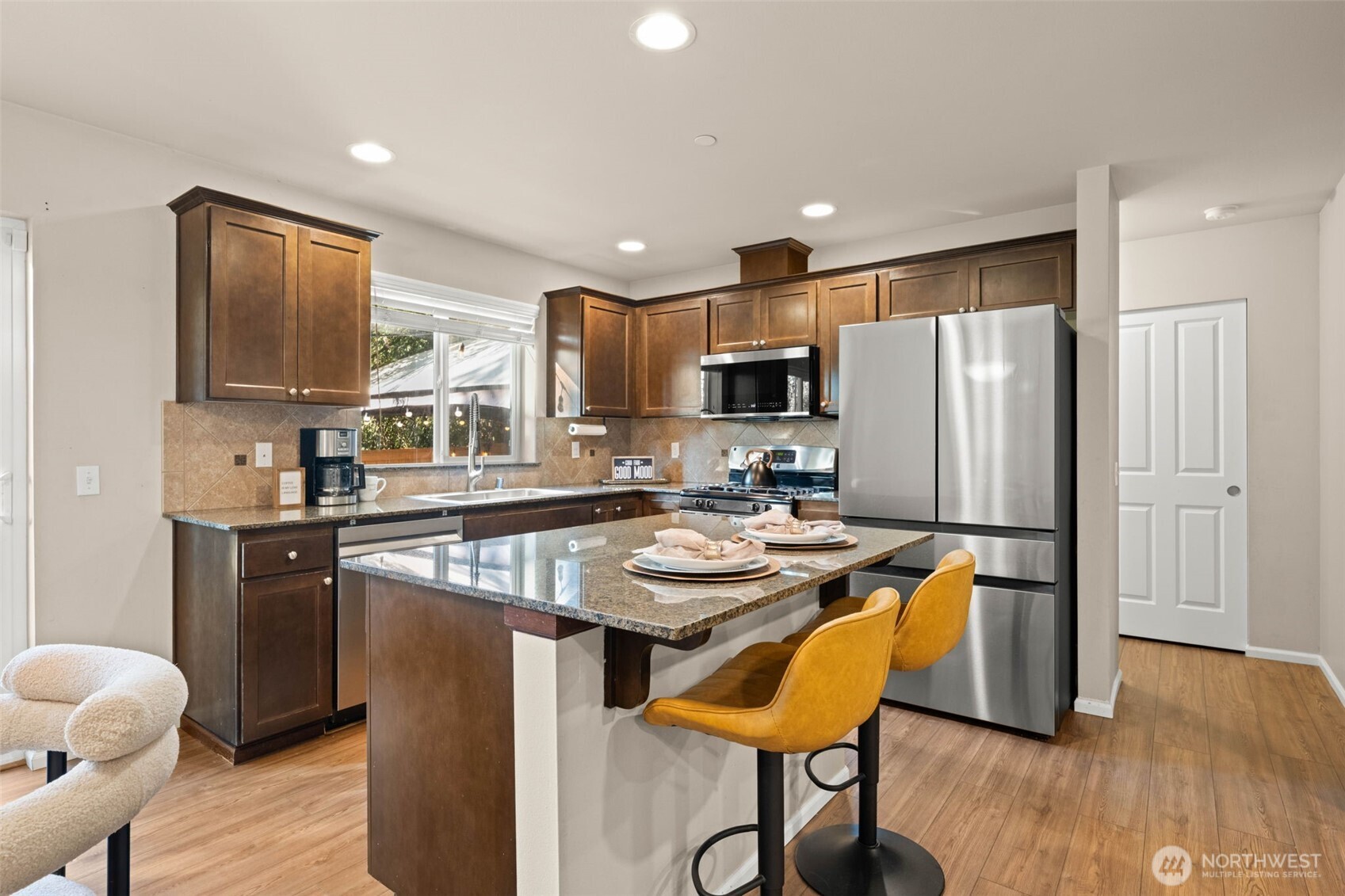 19312 1st Avenue West, Unit 4 Bothell, WA 98012 - Photo 10 of 32 a kitchen with stainless steel appliances granite countertop a refrigerator a stove a sink a dining table and chairs with wooden floor