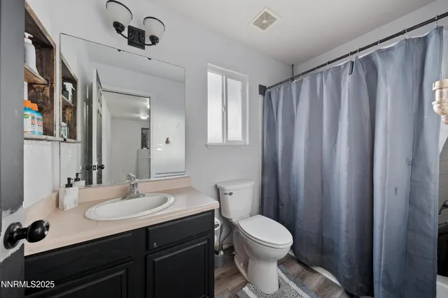 a bathroom with a sink a toilet a mirror and shower curtain