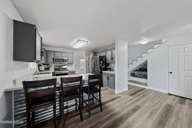 a kitchen with stainless steel appliances a dining table chairs and wooden floor