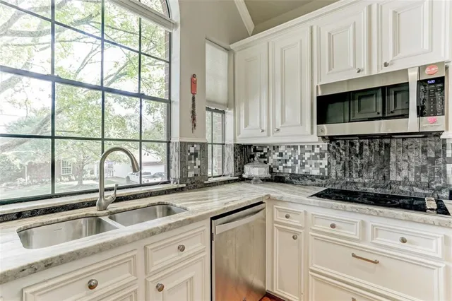 a kitchen with stainless steel appliances granite countertop white cabinets and a sink