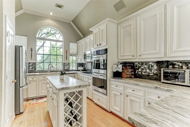 a kitchen with granite countertop white cabinets and window