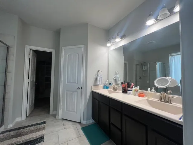 a bathroom with a double vanity sink a mirror and a shower