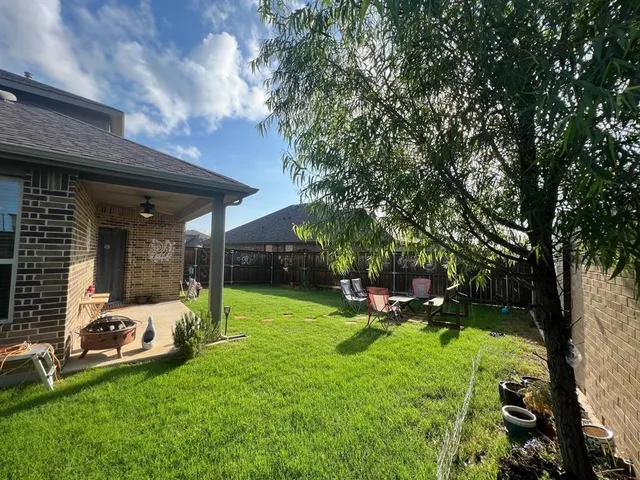 a view of a backyard with table and chairs and a large tree