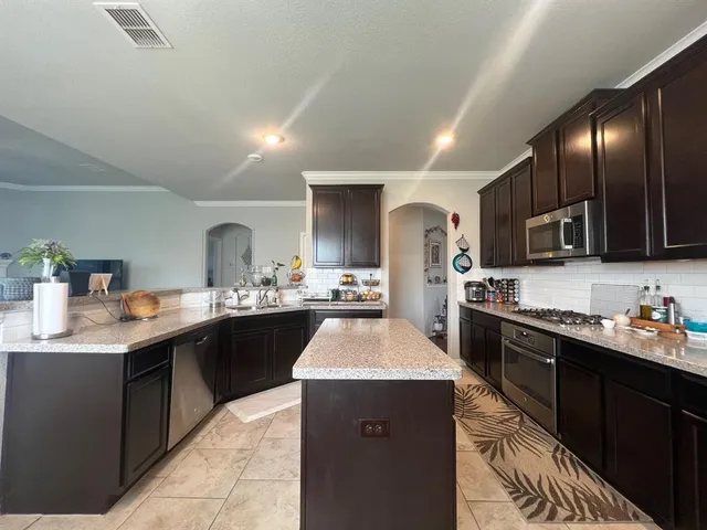 a kitchen with stainless steel appliances granite countertop a sink a stove top oven a counter space and cabinets