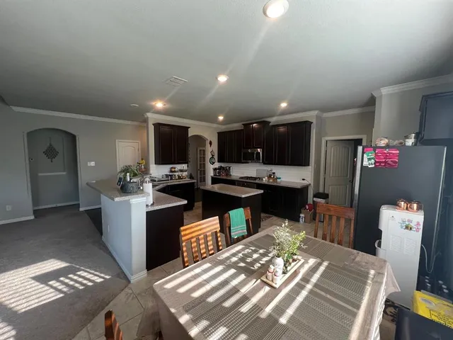 a kitchen with stainless steel appliances kitchen island granite countertop a refrigerator and a stove top oven