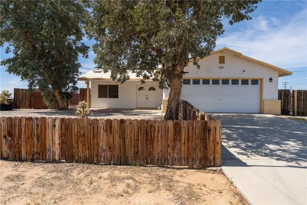a view of a house with a wooden fence and a large tree