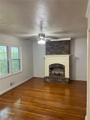 a view of empty room with fireplace and wooden floor