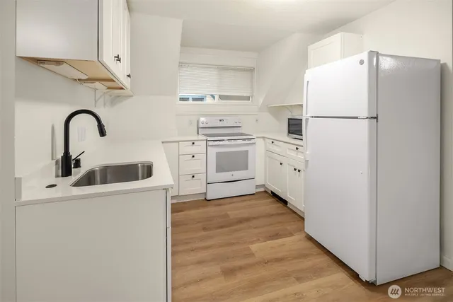 a kitchen with white cabinets and white appliances