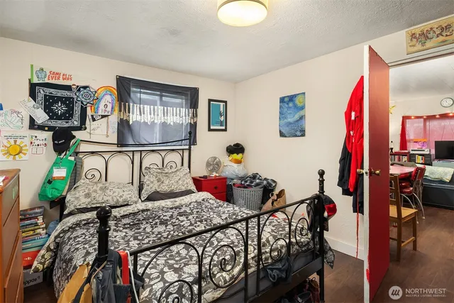 a bedroom with a bed a dresser and potted plants on the table